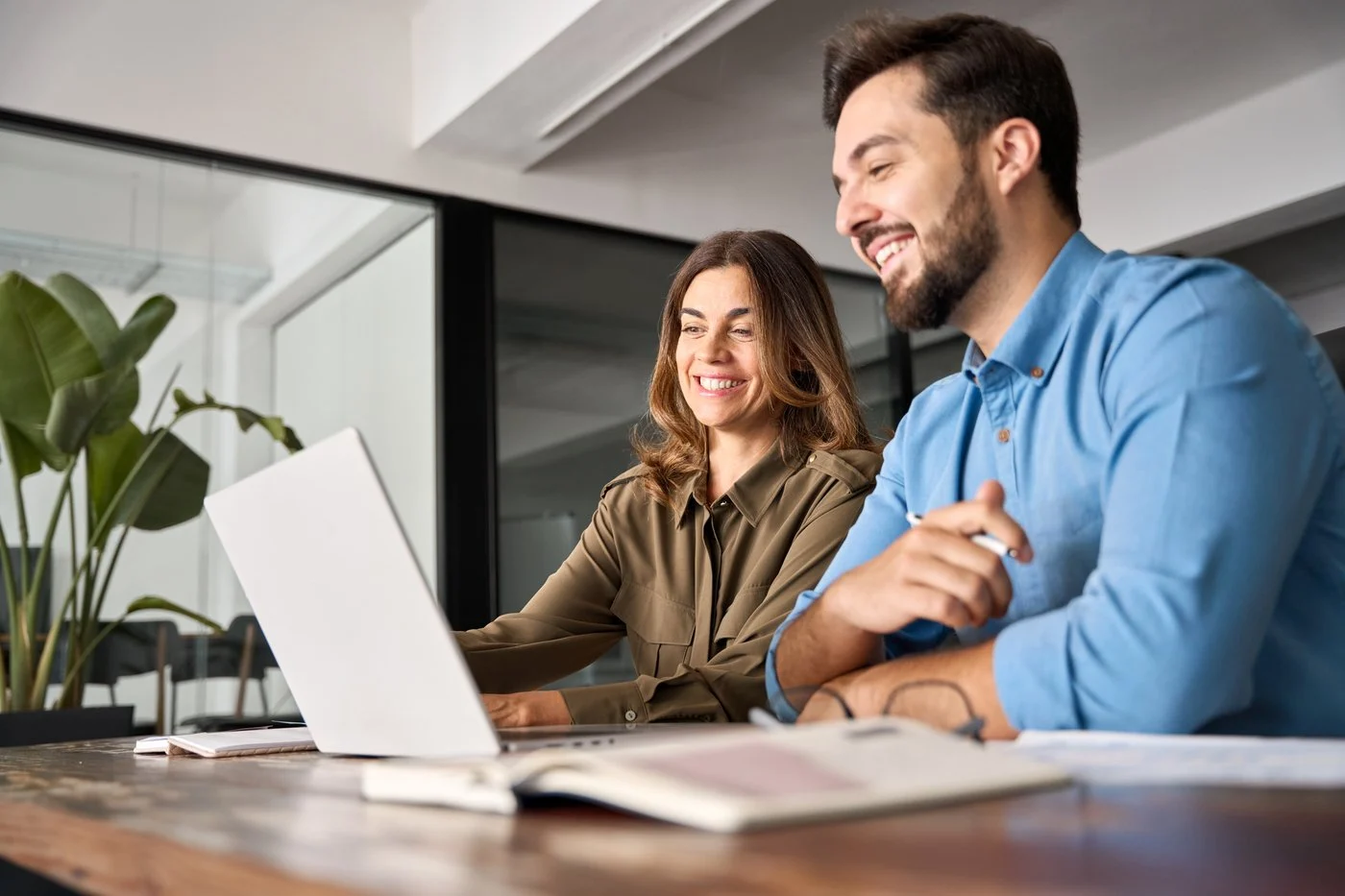 Twee collega's overleggen achter een laptop
